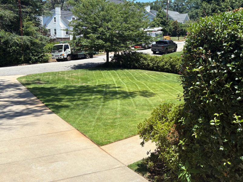 A striped, freshly mown front lawn on a corner lot with the crew truck parked in the driveway